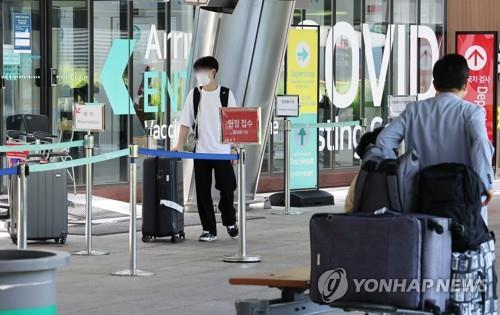 This undated file photo shows international travelers going through a virus test center at an airport. (Yonhap)