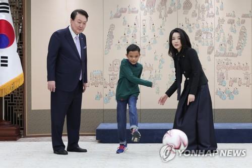 President Yoon Suk Yeol and his wife, Kim Keon Hee, watch Aok Rotha kicking a ball at the presidential office in Seoul on Jan. 31, 2023. (PHOTO NOT FOR SALE) (Yonhap)