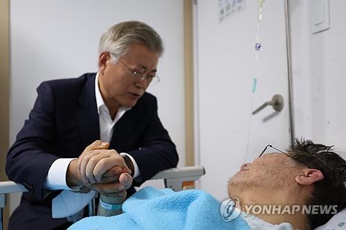 Former President Moon Jae-in (L) holds opposition leader Lee Jae-myung's hand during his visit to a hospital in Seoul on Sept. 19, 2023. Moon reportedly urged Lee to end a hunger strike he has been on for nearly three weeks in protest against government policies. (Yonhap)