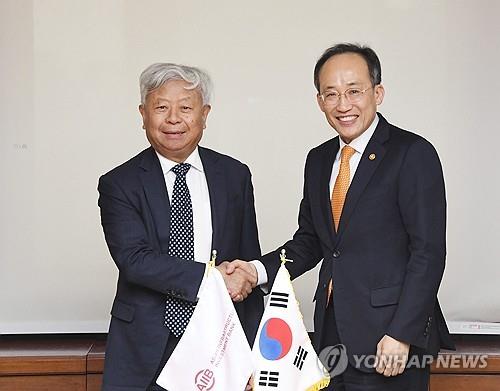This photo, provided by South Korea's finance ministry, shows Finance Minister Choo Kyung-ho (R) shaking hands with Asian Infrastructure Investment Bank President Jin Liqun ahead of their meeting in Seoul on Nov. 27, 2023. (PHOTO NOT FOR SALE) (Yonhap)