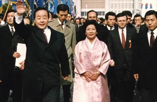 El fallecido expresidente Kim Young-sam (izq.) agita la mano mientras su esposa, Son Myung-soon (centro), está de pie junto a él en esta fotografía de archivo tomada durante la ceremonia de toma de posesión presidencial en la Asamblea Nacional en Seúl el 25 de febrero. 1993. (Yonhap)