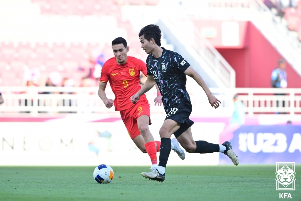 In this photo provided by the Korea Football Association, Kim Min-woo of South Korea (R) dribbles past Behram Abduweli of China during the teams' Group B match at the Asian Football Confederation U-23 Asian Cup at Abdullah bin Khalifa Stadium in Doha on April 19, 2024. (PHOTO NOT FOR SALE) (Yonhap)