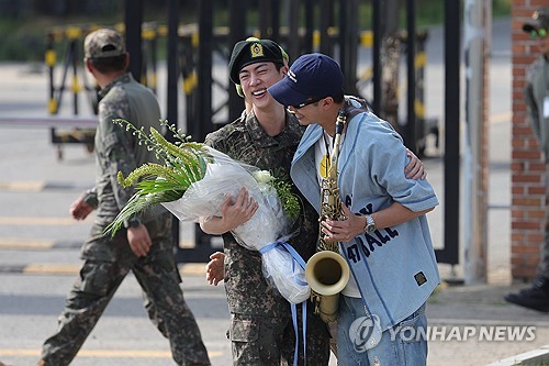 BTS member Jin (L) hugs bandmate RM in front of the main gate of the 5th Army Infantry Division in Yeoncheon, 61 kilometers north of Seoul, on June 12, 2024, after completing his mandatory military service. (Yonhap)