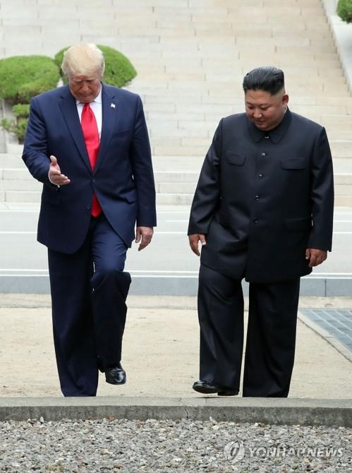 El presidente de Estados Unidos, Donald Trump (izq.), y el líder norcoreano, Kim Jong-un, cruzan la Línea de Demarcación Militar hacia el lado sur de la aldea de tregua de Panmunjom, en la Zona Desmilitarizada, que separa las dos Coreas, el 30 de junio de 2019. (Yonhap)