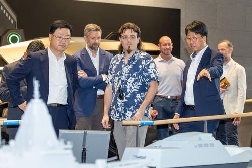 This file photo provided by HD Hyundai Co. on April 7, 2025, shows Palmer Luckey (C), co-founder of U.S. defense firm Anduril Industries Inc., being briefed on the South Korean shipbuilding conglomerate's development projects at a HD Hyundai facility. (PHOTO NOT FOR SALE) (Yonhap)