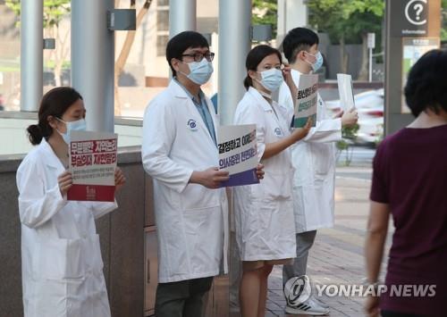 Des médecins brandissent des pancartes critiquant le gouvernement dans un hôpital de Séoul le 26 août 2020, alors que des dizaines de milliers de médecins se sont mis en grève dans tout le pays pour une durée de trois jours plus tôt dans la journée afin de protester contre la réforme du personnel médical du gouvernement. 