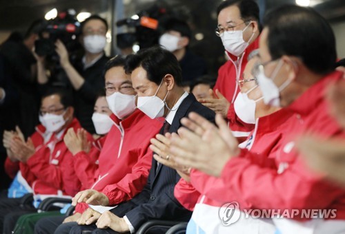 Oh Se-hoon (au centre) se félicite des résultats d'un sondage de sortie des urnes favorables à sa victoire aux élections partielles pour le siège de maire de Séoul, le mercredi 7 avril 2021. 