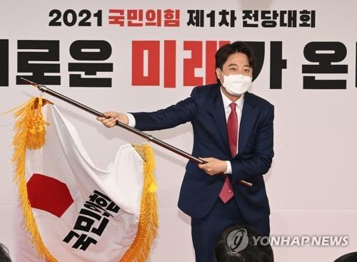 Lee Jun-seok brandit le drapeau du Parti du pouvoir du peuple (PPP) après avoir remporté la présidence de la formation conservatrice lors d'une convention du parti, le 11 juin 2021.