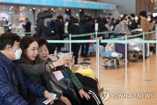 Des membres d'une famille prennent des selfies à l'aéroport international d'Incheon, le mardi 31 janvier 2023, avant de partir pour un voyage. 
