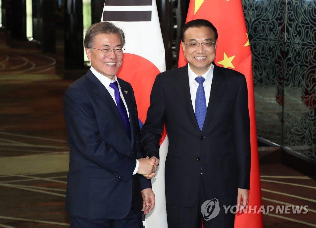 中国の李首相（右）と握手する文大統領＝１３日、マニラ（聯合ニュース）