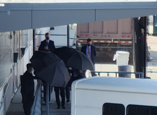 傘に遮られ、空港を出る金氏の顔を判別できない＝１９日、ワシントン（聯合ニュース）