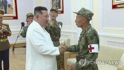 北朝鮮の金正恩（キム・ジョンウン）国務委員長（朝鮮労働党総書記、手前左）は先ごろ、新型コロナウイルスの「非常防疫戦」で任務を果たした軍医務部隊の戦闘員らをねぎらった（朝鮮中央テレビの映像から）＝（聯合ニュース）≪転載・転用禁止≫