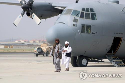 미국 철수후 카불 공항에 버려진 군 수송기 앞을 걸어가는 탈레반 관리들