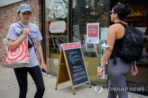구직 간판이 붙은 가게 앞 지나가는 행인