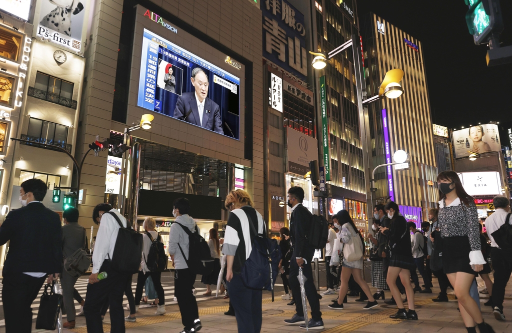 (도쿄 교도=연합뉴스) 9일 저녁 퇴근길 인파로 붐비는 도쿄 신주쿠 거리의 한 건물 벽면 TV에 긴급사태 연장 관련 기자회견을 하는 스가 요시히데 총리의 모습이 비치고 있다. 