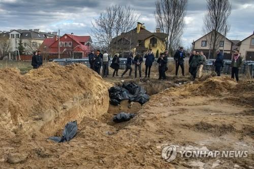 Ukrainian Bucha residents inspect a mass grave of civilians