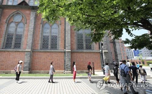 Las personas mantienen una distancia prudente entre sí mientras esperan en fila para asistir a misa, el 28 de junio de 2020, en la catedral de Myeongdong, en el centro de Seúl, en medio de la crisis del nuevo coronavirus.