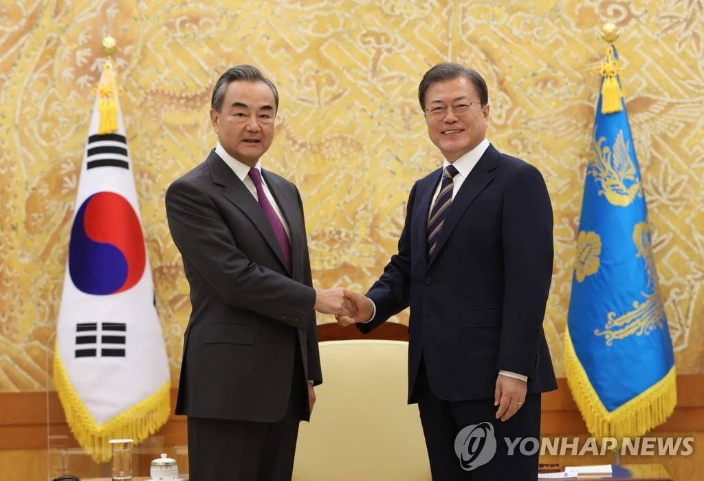 El presidente surcoreano, Moon Jae-in (dcha.), estrecha la mano del ministro de Asuntos Exteriores de China, Wang Yi, durante una visita de cortesía de Wang, el 26 de noviembre de 2020, en la oficina presidencial, Cheong Wa Dae, en Seúl.