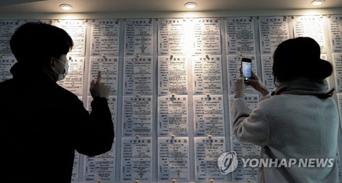 La foto de archivo, tomada el 13 de enero de 2021, muestra a unas personas mirando información laboral en una oficina de empleo, en Seúl.
