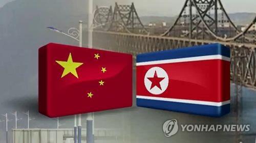 Una imagen, proporcionada por la Televisión de Noticias Yonhap, muestra las banderas de China y Corea del Norte, con un puente transfronterizo a mitad del río Yalu, en el fondo. (Prohibida su reventa y archivo)