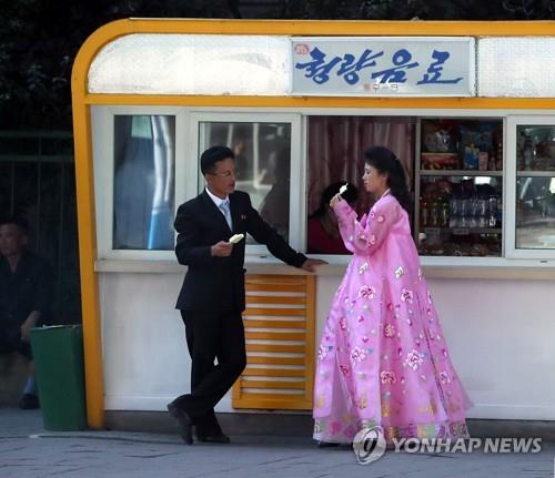 La foto de archivo, tomada el 18 de septiembre de 2018, muestra a norcoreanos disfrutando de unos helados en una calle en Pyongyang. La prensa surcoreana visitó Pyongyang para cubrir el viaje de tres días del entonces presidente Moon Jae-in, que se inició el mismo día por la mañana, para celebrar su tercerca cumbre intercoreana con el presidente del Comité de Asuntos de Estado norcoreano, Kim Jong-un. (Foto del cuerpo de prensa. Prohibida su reventa y archivo)