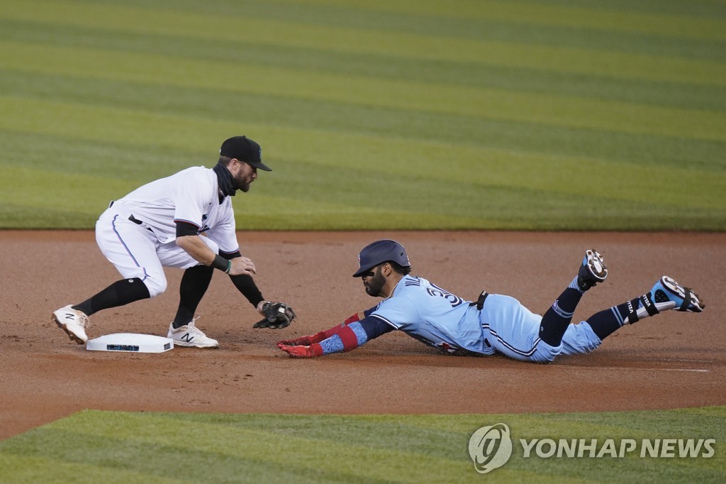 In this Associated Press photo, Jonathan Villar of the Toronto Blue Jays (R) is tagged out by Miami Marlins second baseman Jon Berti at second base after attempting to stretch out a single during the top of the first inning of a Major League Baseball regular season game at Marlins Park in Miami on Sept. 2, 2020. (Yonhap)
