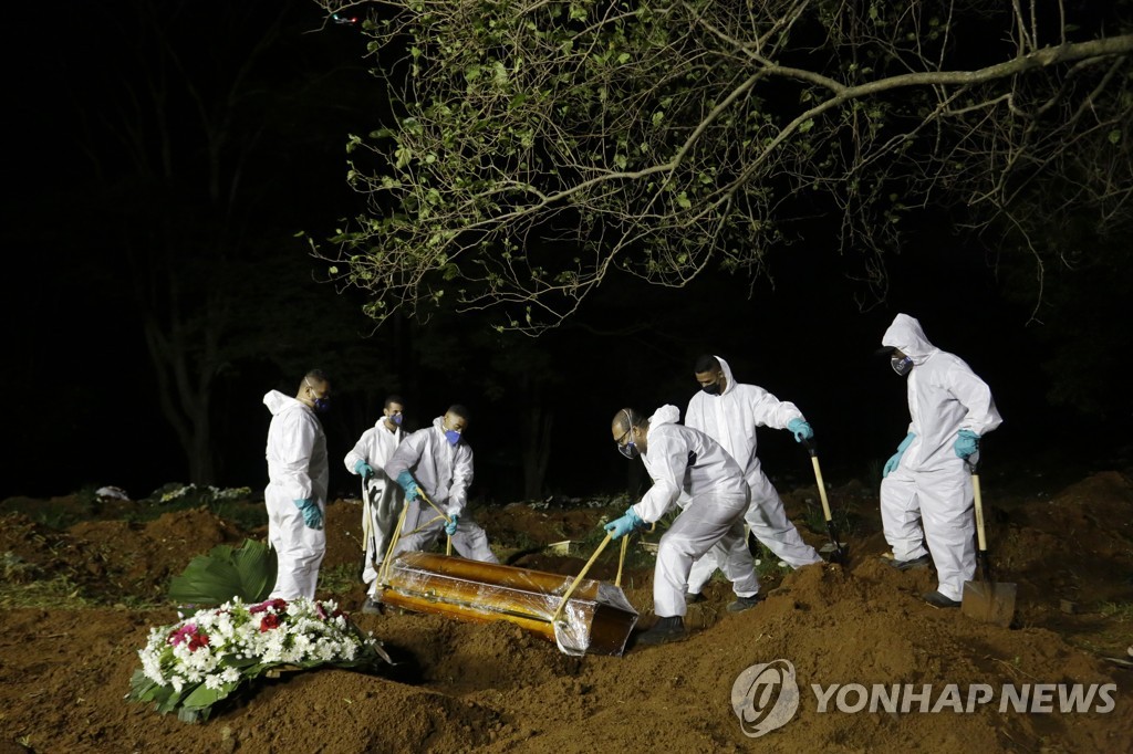 지난달 31일 저녁 브라질 상파울루 빌라 포모사 공동묘지에서 사람들이 시신을 안장하고 있다.
