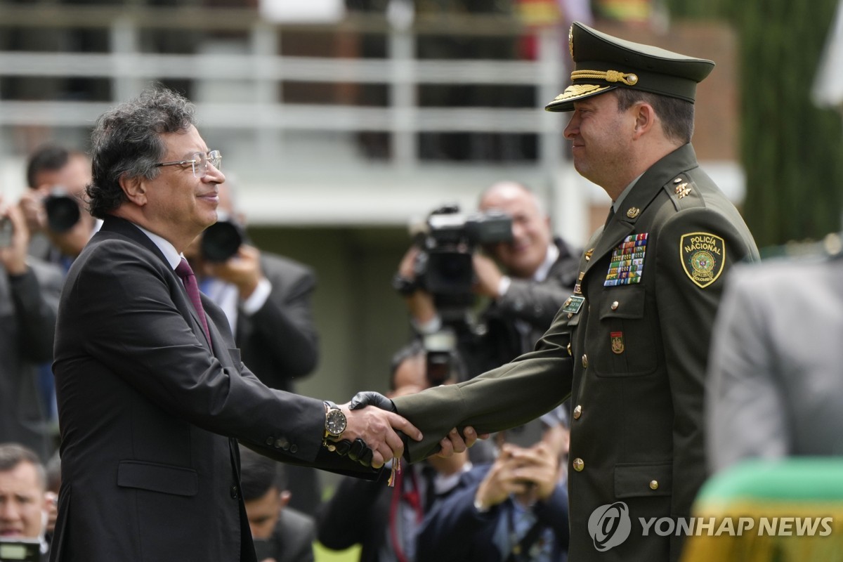 18일(현지시간) 신임 경찰청장과 악수하는 콜롬비아 대통령(왼쪽)