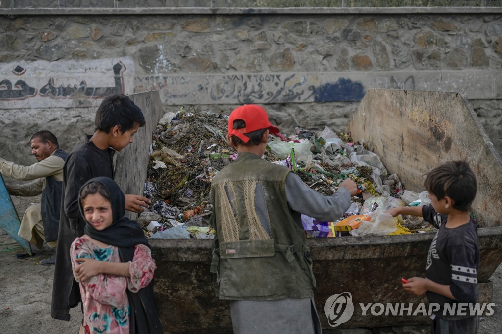 This AFP photo shows children collecting food and recyclable materials from garbage near the airport in Kabul on Sept. 21, 2021. (Yonhap) 