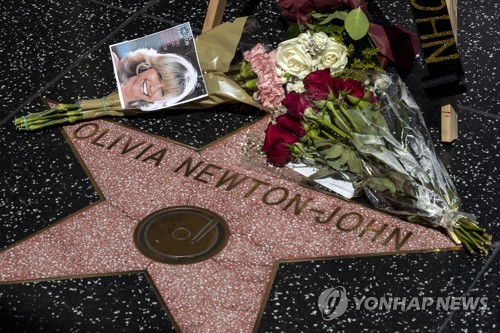 미국 로스앤젤레스 할리우드 명예의 거리에 새겨진 뉴턴 존의 이름. 옆에 사진과 꽃이 놓여 있다. 
