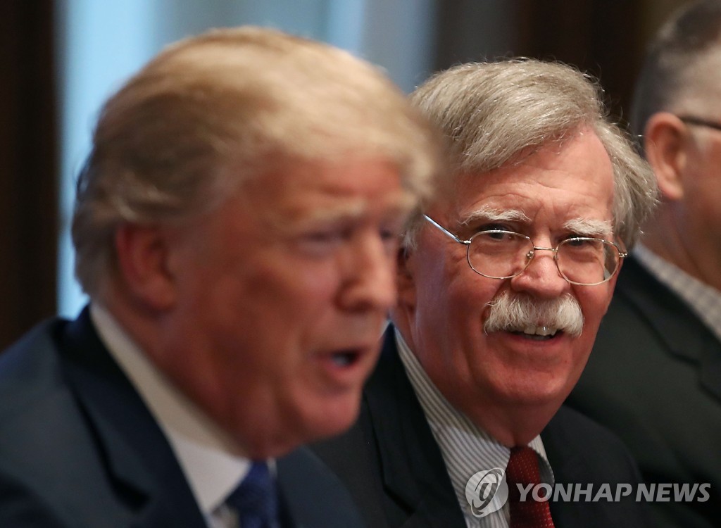 This AFP photo shows then-U.S. National Security Adviser John Bolton (R) listening to President Donald Trump during a White House meeting on April 09, 2018. (Yonhap)