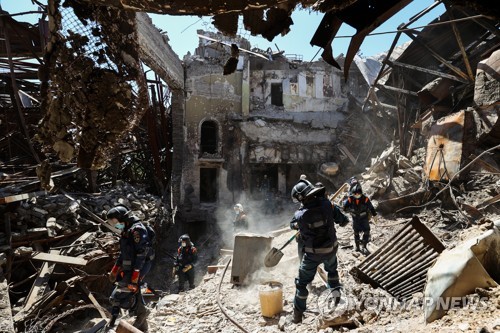 러시아군의 폭격으로 파괴된 마리우폴 극장 내에서 잔해를 치우는 구급대원들