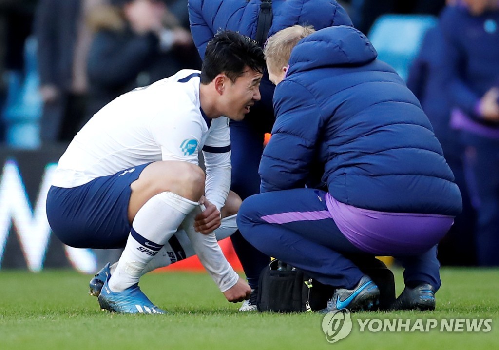 In this Reuters file photo from Feb. 16, 2020, Son Heung-min of Tottenham Hotspur (L) winces in pain while grabbing his right arm during a Premier League match against Aston Villa at Villa Park in Birmingham, England. (Yonhap)