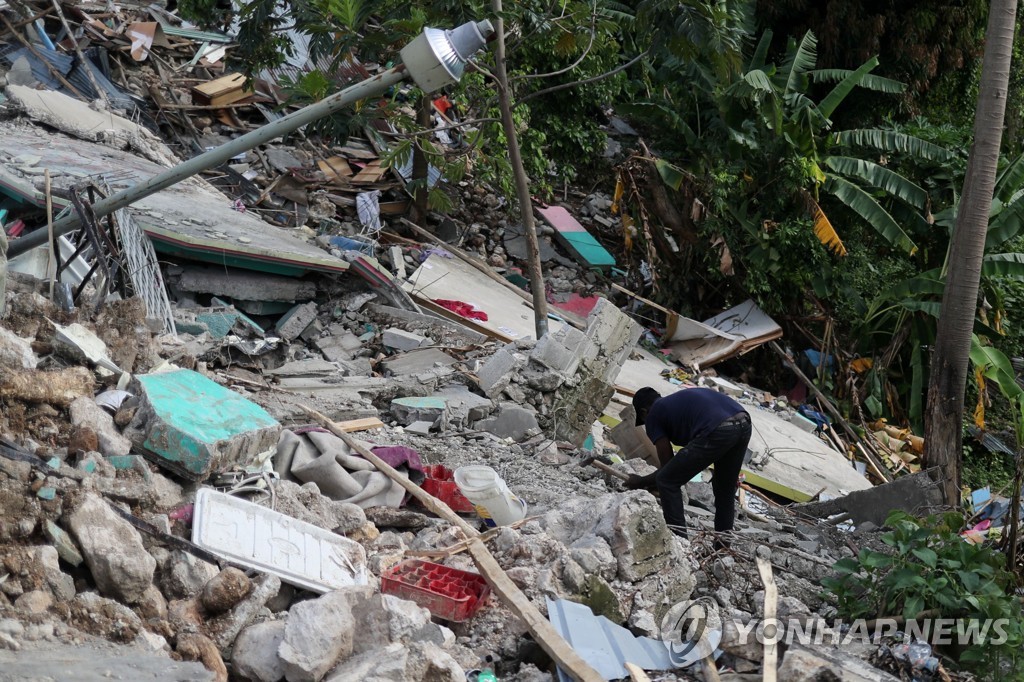 20일(현지시간) 무너진 집 잔해 사이를 뒤지는 아이티 레카이 주민