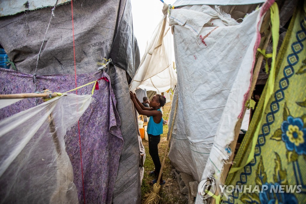 22일(현지시간) 천막 손보는 아이티 레카이의 지진 이재민 어린이 