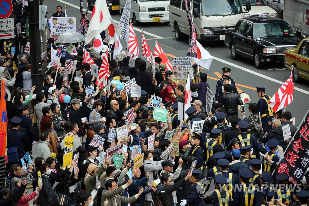 2016년 3월 일본 도쿄도(東京都) 주오(中央)구 긴자(銀座) 거리에서 재일 조선학교 보조금 중단 등을 요구하는 시위대(오른쪽)가 행진하고 있고 이에 반대하는 시민들(왼쪽)이 피켓을 들고 항의하고 있다. [연합뉴스 자료사진]