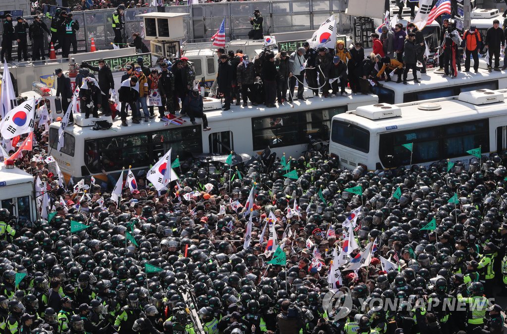 警察のバスに上る弾劾反対集会の参加者＝１０日、ソウル（聯合ニュース）