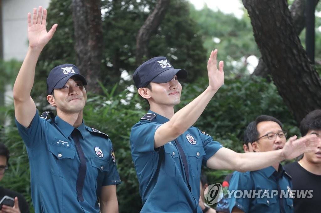 手を振るチャンミンさん（右）とシウォンさん＝１８日、ソウル（聯合ニュース）