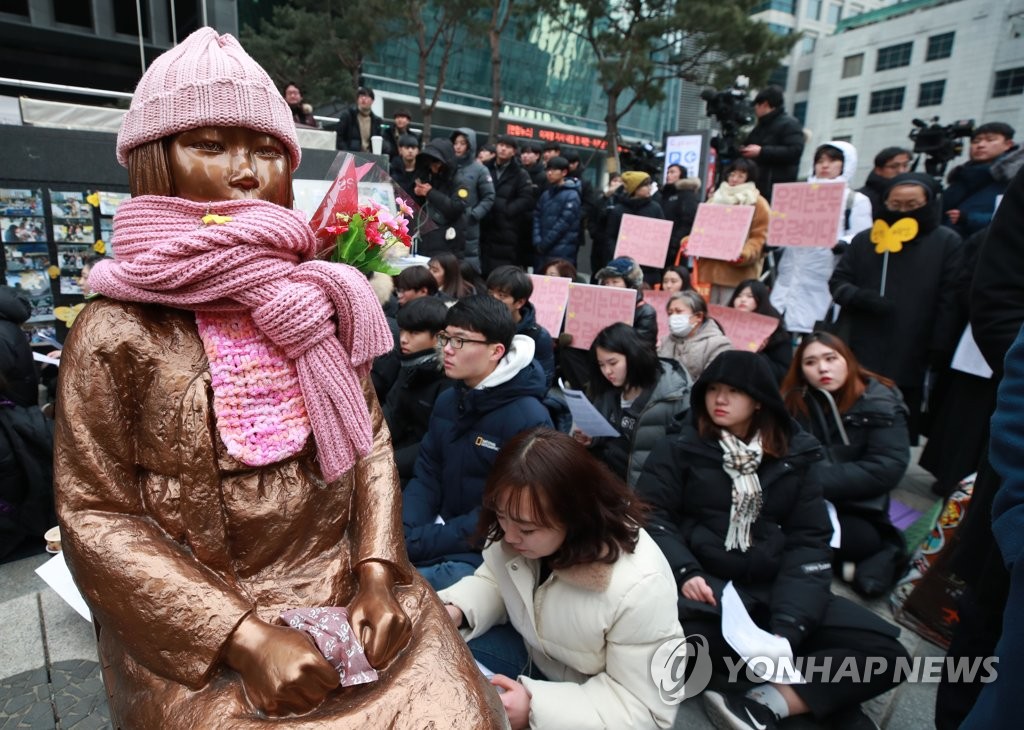慰安婦被害者を象徴する少女像のそばに集まった参加者ら＝９日、ソウル（聯合ニュース）