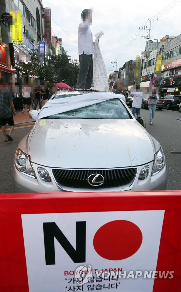 In this photo taken July 23, 2019, a protestor holds a performance against Japanese products on top of a Lexus sedan in Incheon, just west of Seoul. (Yonhap)