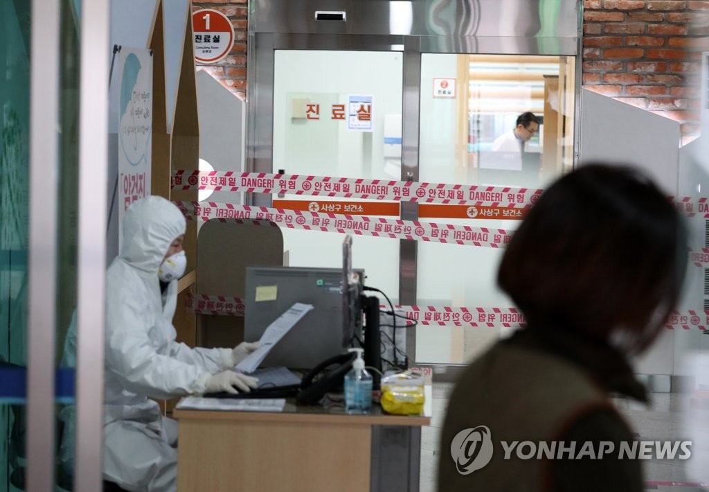 A medical staff member wearing a protective suit and mask sits outside a public health clinic in Busan, 450 kilometers southeast of Seoul, on Jan. 30, 2020, as the country is on heightened alert to counter the spread of the coronavirus outbreak. (Yonhap)