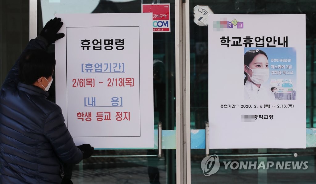A school official posts a class suspension notice on the doors of a middle school in Seongbuk Ward in Seoul on Feb. 6, 2020. (Yonhap)