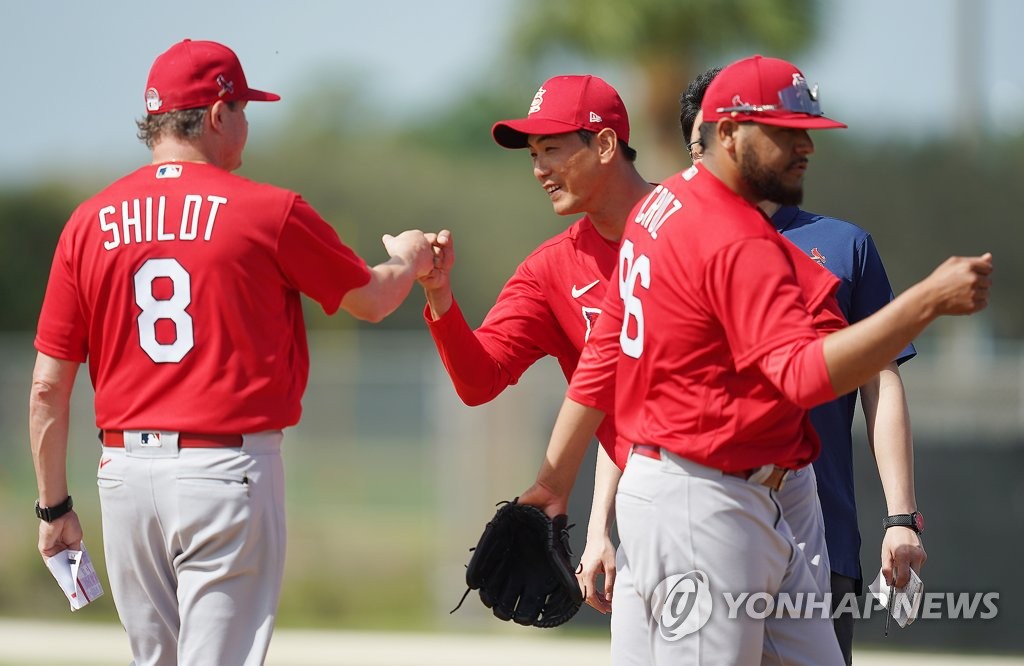 Mike Shildt (L), manager of the St. Louis Cardinals, bumps fists with South Korean pitcher Kim Kwang-hyun (C) during spring training at Roger Dean Chevrolet Stadium in Jupiter, Florida, on Feb. 12, 2020. (Yonhap)