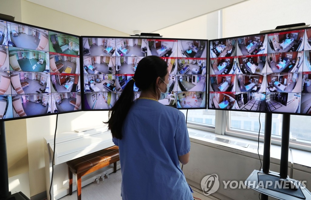 资料图片：医务人员通过大屏幕实时监控新冠患者病情状况。 韩联社