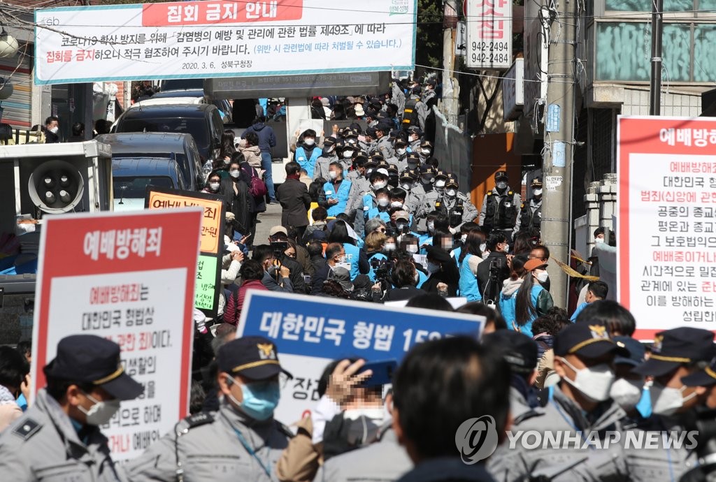 Des policiers et des fidèles se font face devant la Sarang Jeil Church dans le quartier de Seongbuk, dans le nord-est de Séoul, le 29 mars 2020.