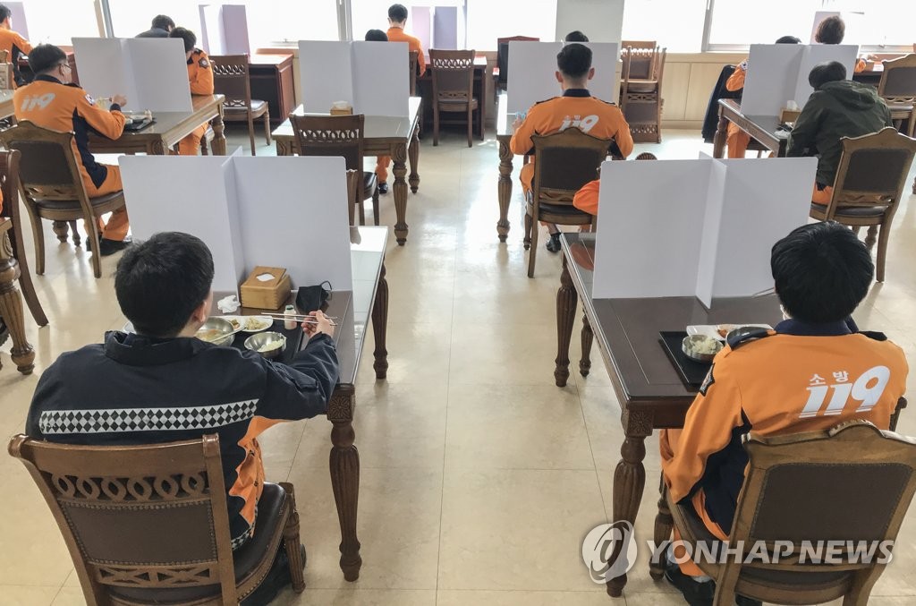 Firefighters at Eunpyeong Fire Station are seen eating lunch at separate tables in this photo taken on April 1, 2020. (Yonhap)