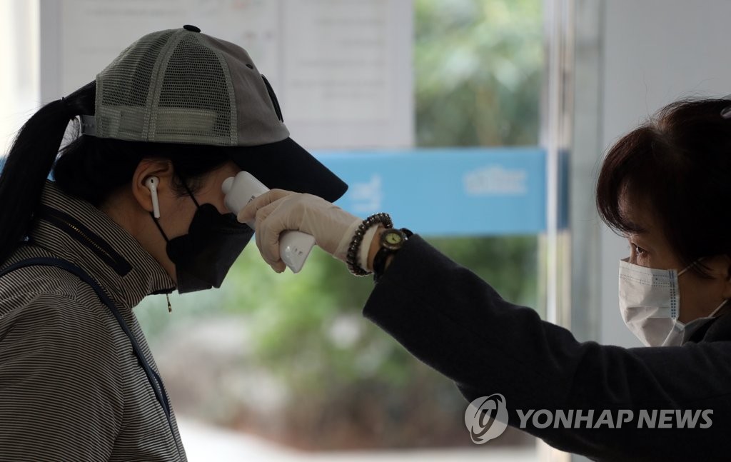 期日前投票所で係員が有権者の体温検査を行っている＝１０日、ソウル（聯合ニュース）