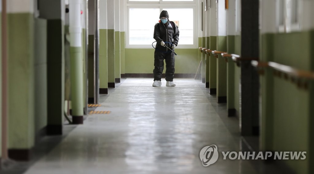 A military medical official disinfects a hallway inside a middle school in Daegu on April 13, 2020. (Yonhap)