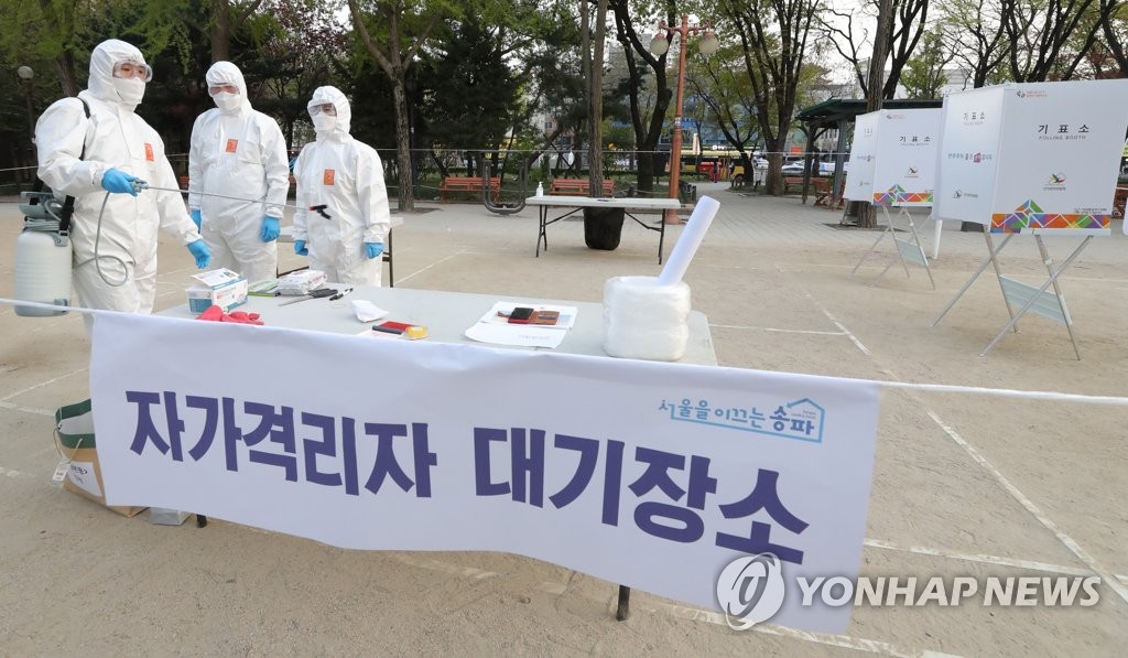 Poll workers disinfect a polling zone in eastern Seoul before voters under self-quarantine measures cast their ballots on April 15, 2020. (Yonhap)