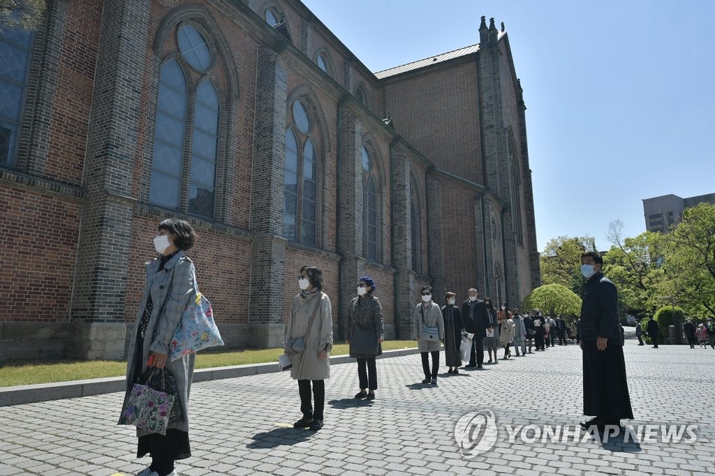 People wait in line to participate in a Mass at Myeongdong Cathedral in central Seoul on April 26, 2020, in this file photo. (Yonhap)